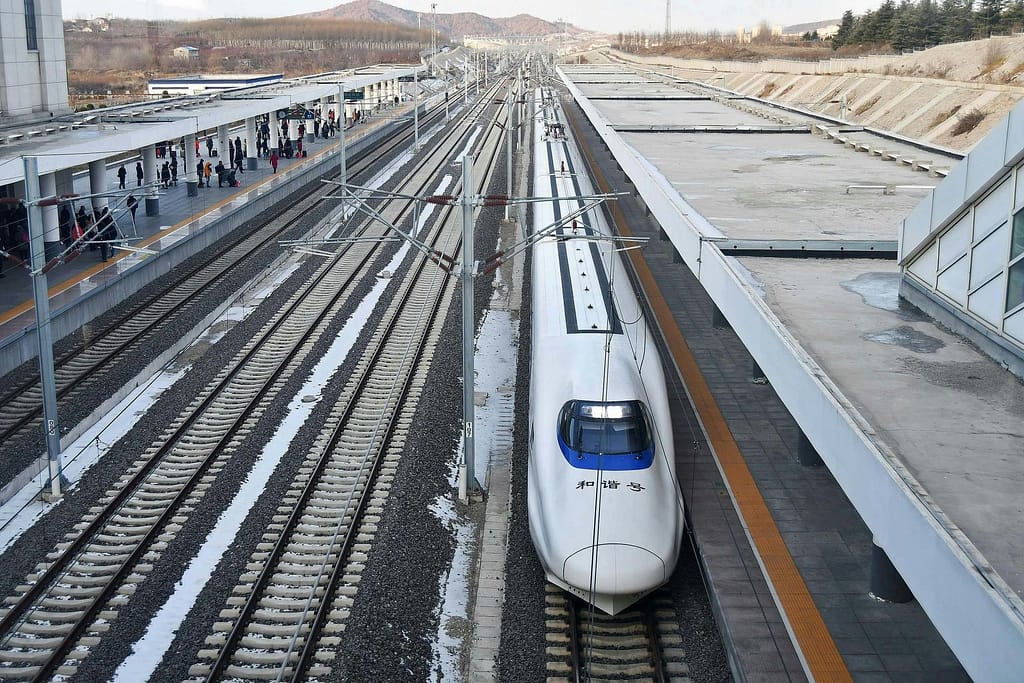 A high-speed bullet train at a modern railway station during the day, showcasing efficient public transport.